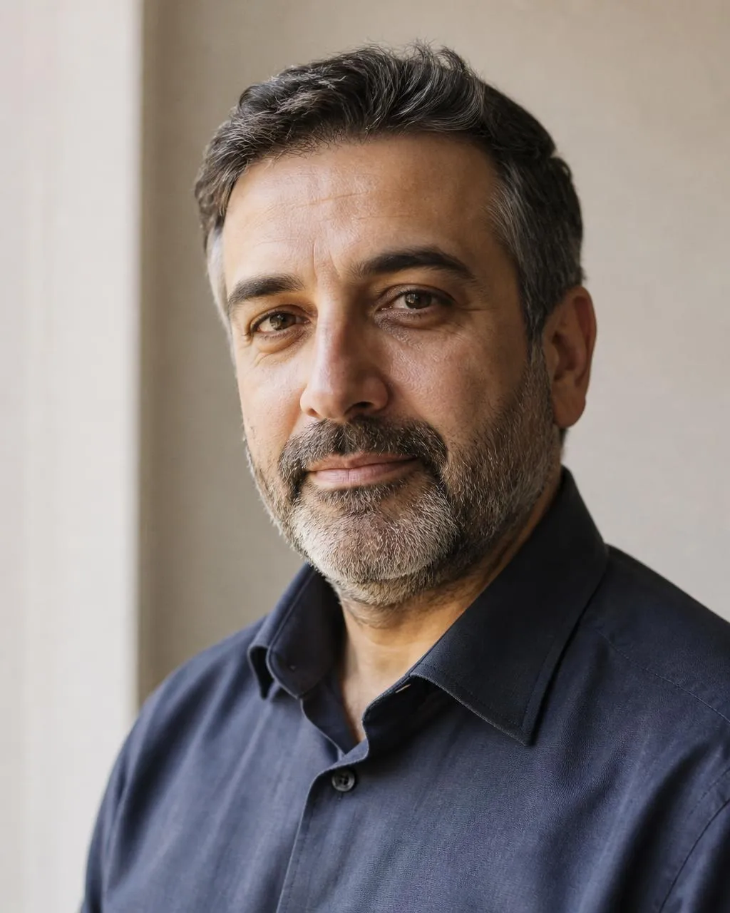 A specialist in a charcoal jacket against a bone-white wall.